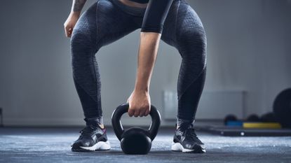 Person squatting down to grab a kettlebell