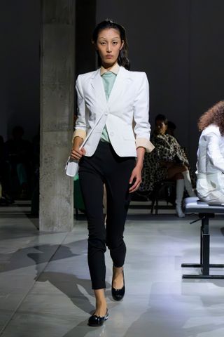 Marni model wearing a white blazer with black cigarette pants and flats.