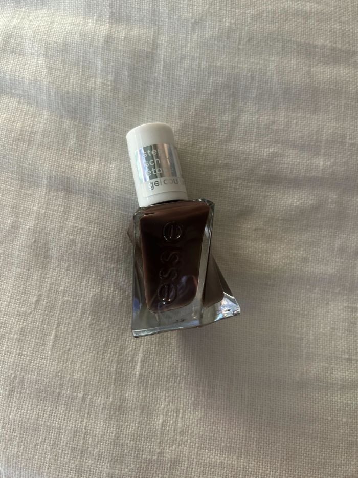 The Essie All Checked Out nail polish on a white linen background