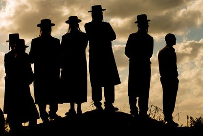 Ultra-Orthodox Jewish men stand on a hill.
