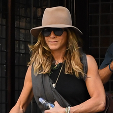 Jennifer Aniston in New York wearing capri pants, flip flops, and a black tank top