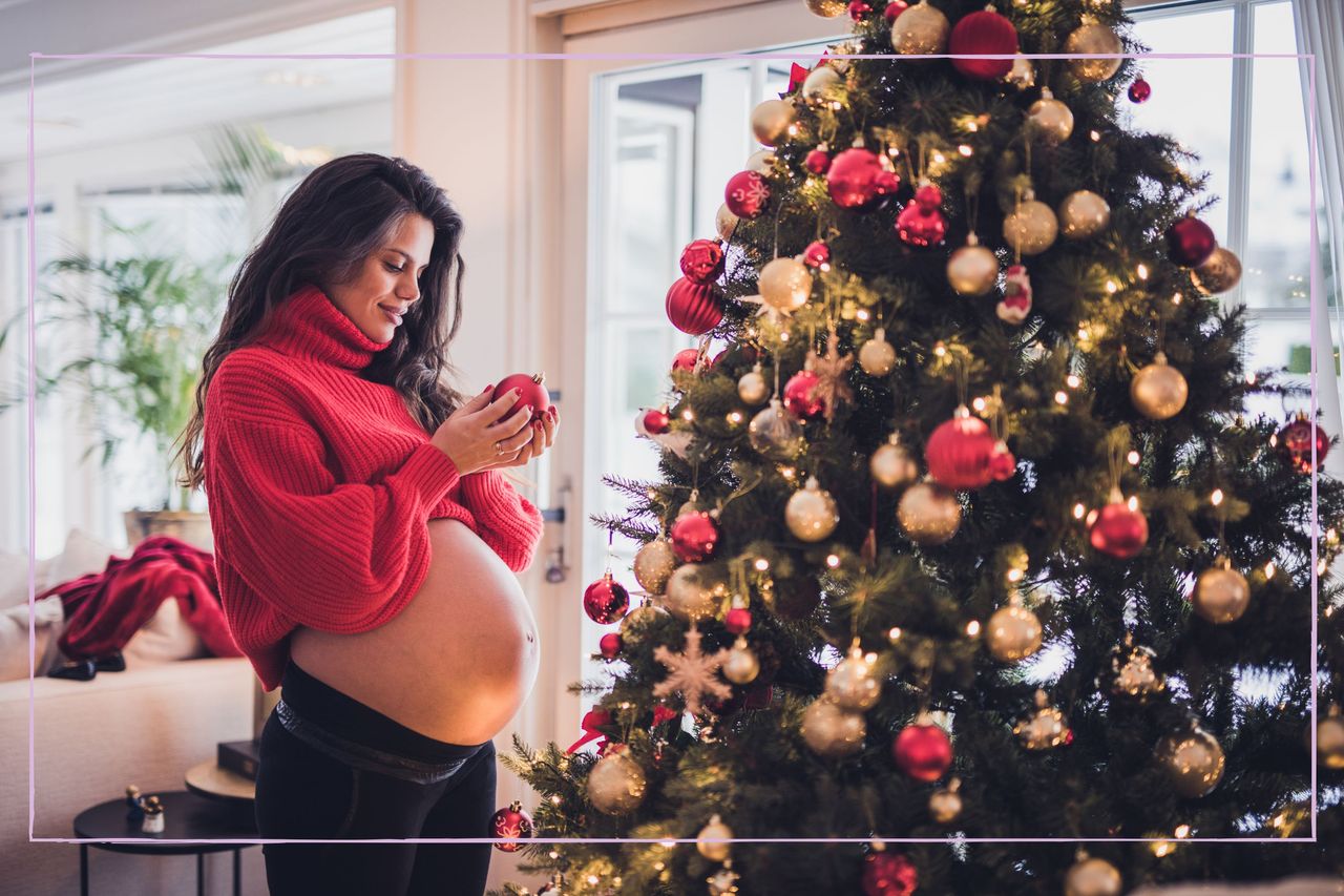 A pregnant woman decorating a Christmas tree