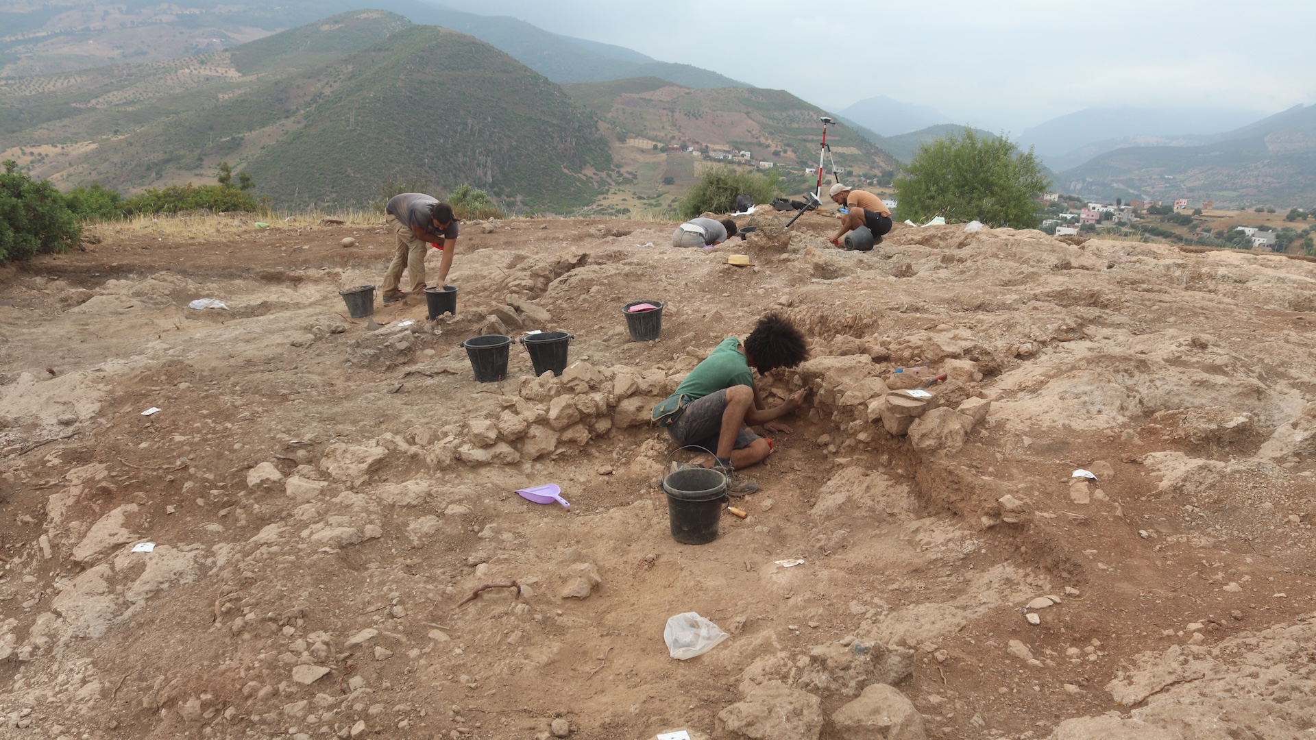 a group of people excavate a site in a hilly region