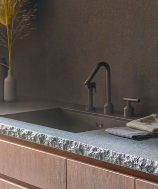 Close up of raw concrete surface edge on kitchen countertop, wooden cabinetry