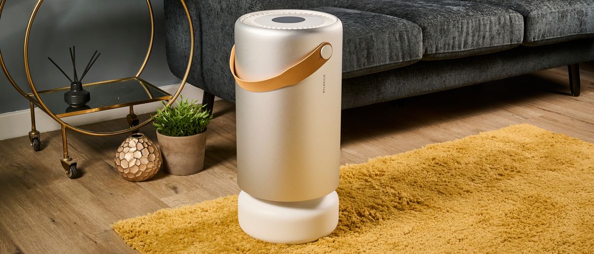 Image shows the Molekule Air Pro air purifier sitting on a mustard colored rug in a living room.