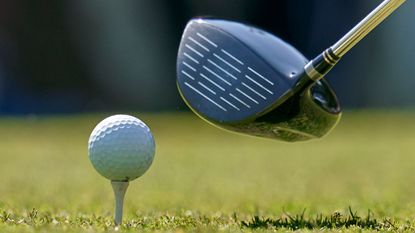 A close-up of a driver next to a ball on a tee