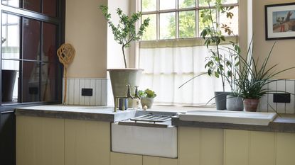 Grey shaker kitchen with white belfast sink and window with white shutters.