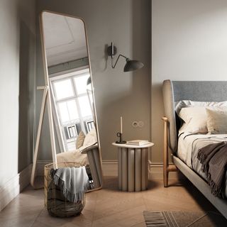 a scandi bedroom with a full length mirror large wood tiles bed and nightstand with wall sconce