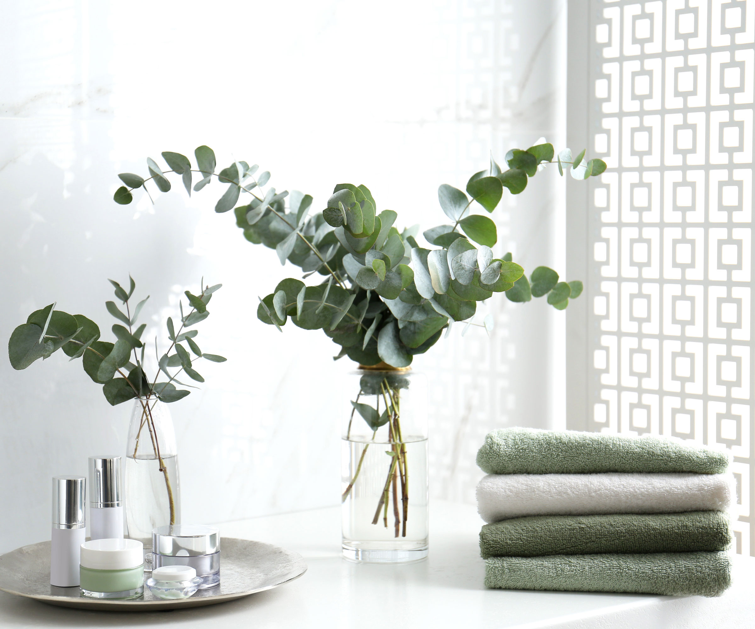eucalyptus in vases in bathroom with towels