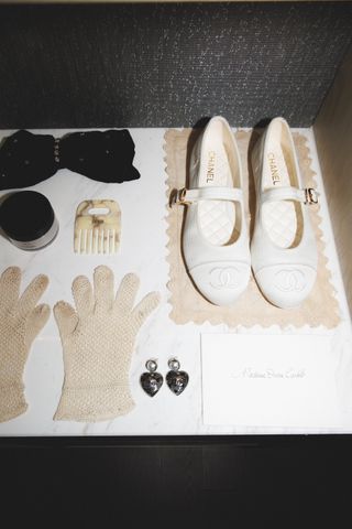 Orion's chanel accessories laid out on a table, including Chanel mary janes, chanel heart earrings, and a pair of white knit gloves