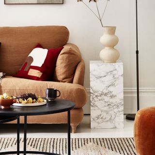 brown sofa with marble wrap side table and vase with black coffee table