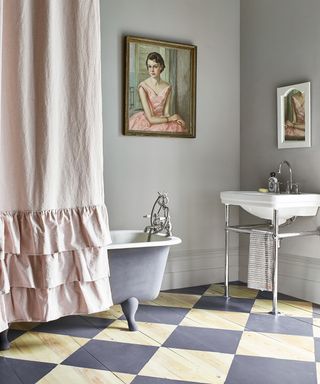 A traditional-style bathroom with checkerboard painted wooden flooring and a freestanding bath with a shower curtain