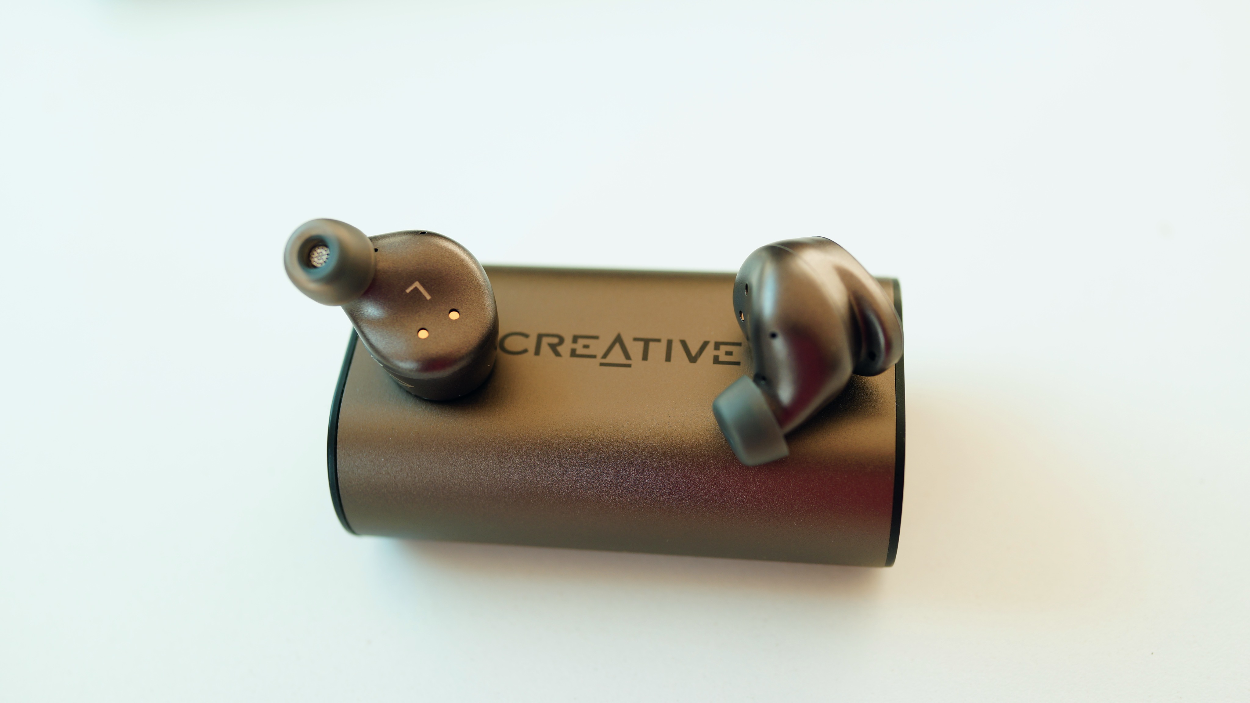 Et par Creative Outlier Pro øretelefoner ligger oven på ladeetuiet på et hvidt bord