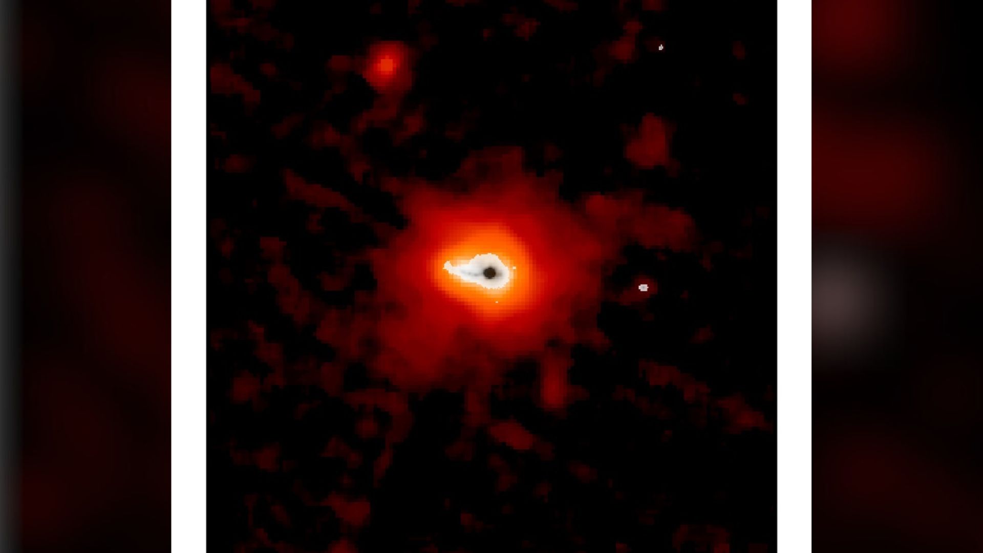 A glowing dark dot surrounding by blobs of white, orange and red light sits on a dark background