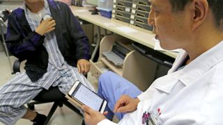 Dr. Li Dianyou, of Ruijin Hospital in Shanghai, China, uses a computer tablet to adjust the settings of a deep brain stimulation device implanted in the brain of a patient who underwent the procedure to treat his methamphetamine addiction.