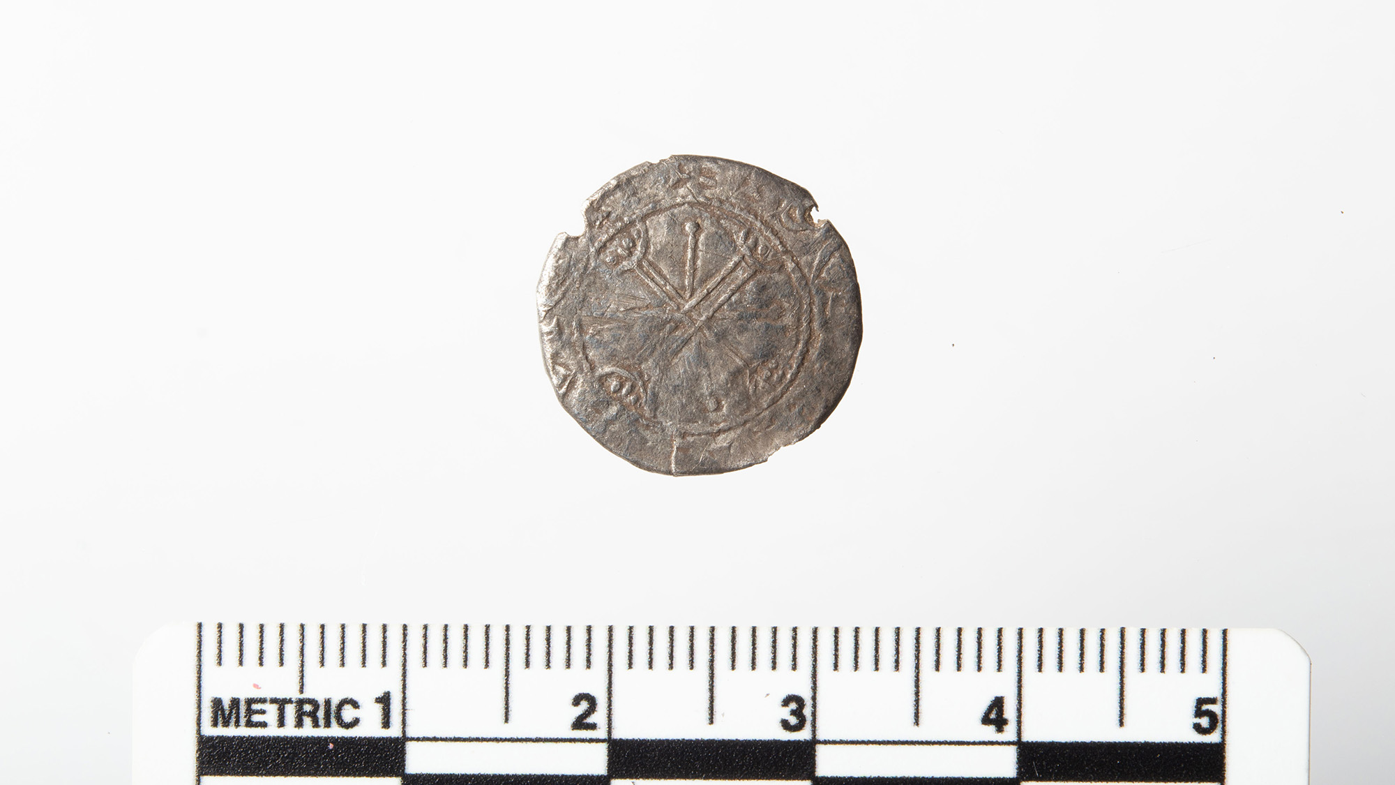 A close up of a silver coin next to a measuring tape