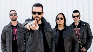 Black Star Riders standing against a white wall, with Ricky Warwick pointing at the camera