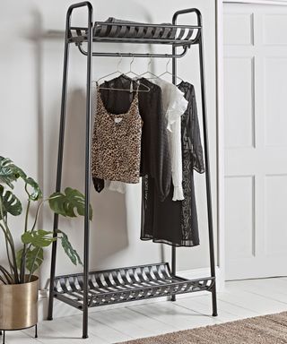 A black industrial style wrought iron clothing rail by Cox and Cox to organize clothes in a small bedroom for couples