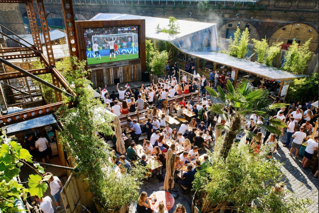 an artist's rendering of what the brewery will look like during the match, with plenty of open air benches filled with people watching the match on the big screen