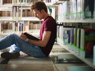 A college-age man studies in a library
