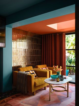 A living room with a zellige tiled wall, an orange ceiling, and teal walls