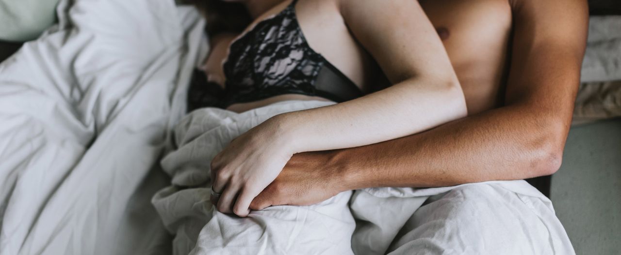 cropped view of couple spooning in bed