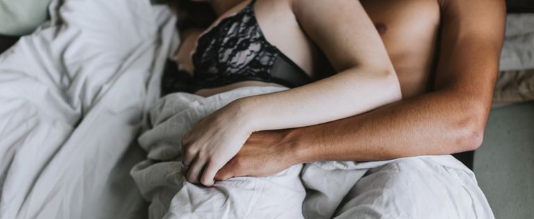 cropped view of couple spooning in bed
