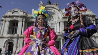 To celebrate the Day of the Dead, two women are dressed as catrinas on the esplanade of the Palacio de Bellas Artes in Mexico City on Nov. 1, 2020.