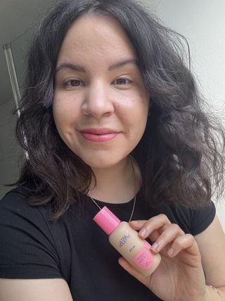 mica holding a bottle of Ultra Violette Daydream Screen SPF 50 Tinted Veil