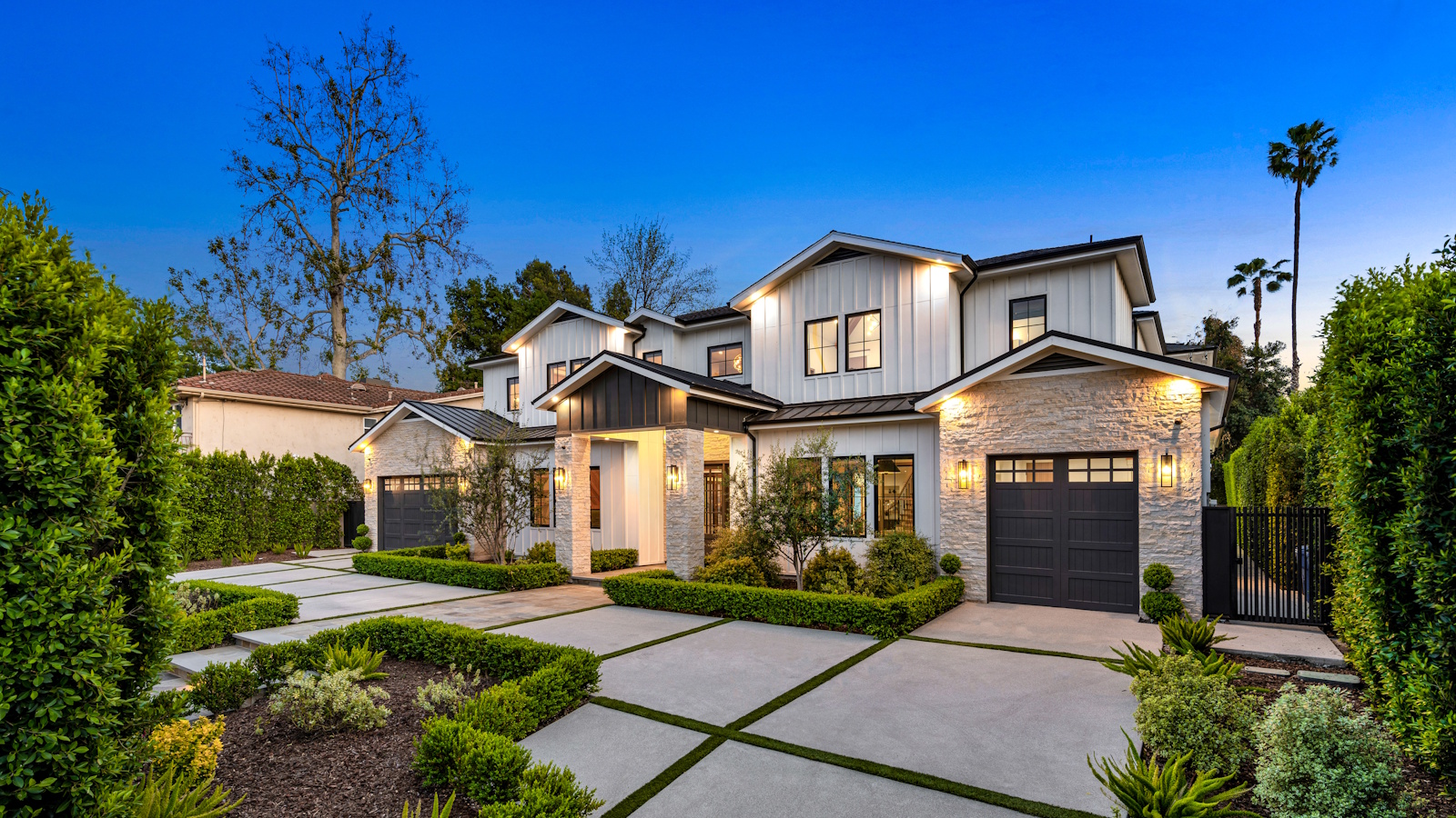 Exterior photo of a home in Beverly Hills at dusk, with neat privet planting