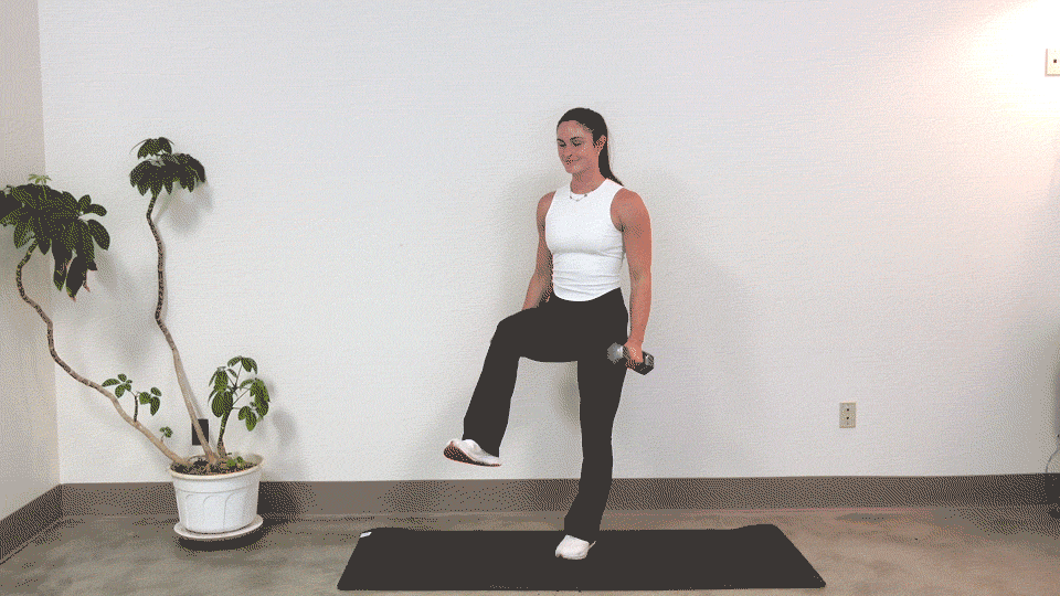 trainer Kirra Mitlo doing dumbbell bicep curls on one leg