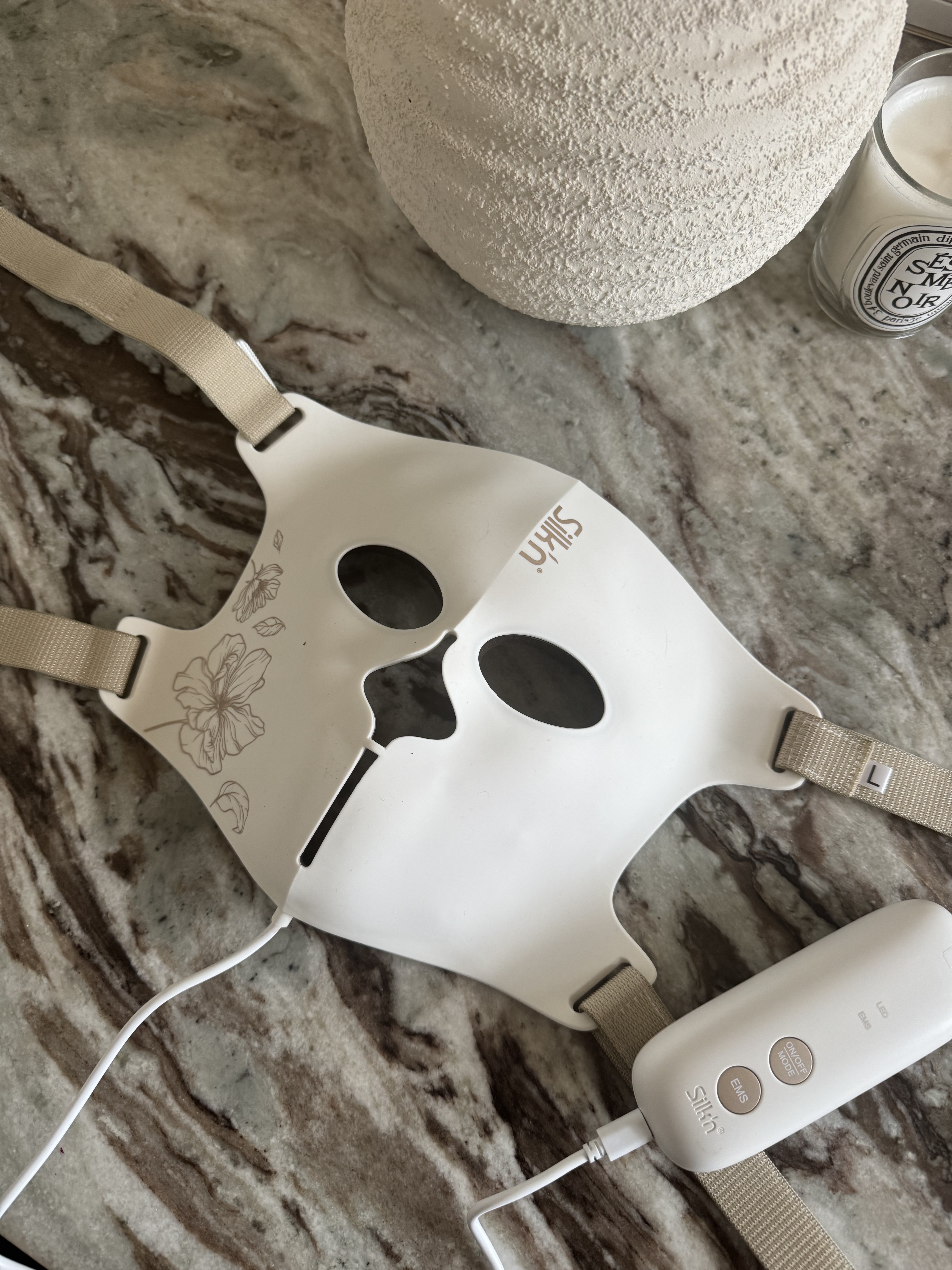 The Silk'n LED EMS face mask on a marble table