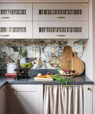 A pink kitchen with a gold hanging rail on the wall