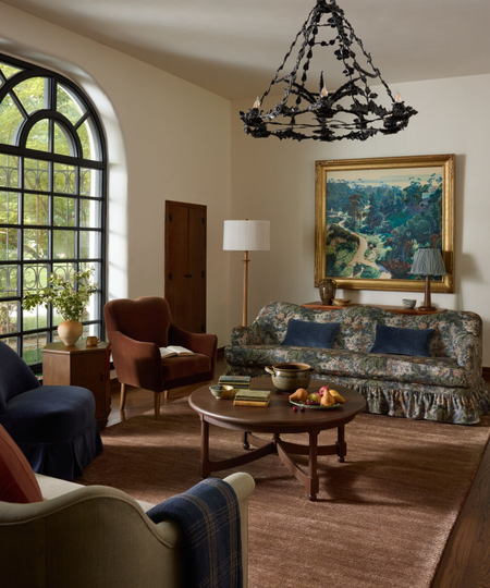 a vintage-inspired living room with a brown rug, a floral couch, and a decorative chandelier