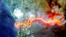 A satellite photo of an island with a giant river of orange lava 