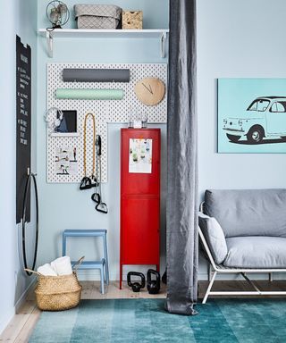 A home gym setup in a blue living room with dark grey curtain divider, red retro locker, white pegboard