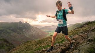 A man runs down a rocky mountain path in a mountainous area