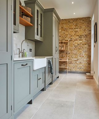 Sage utility room with bare brick walls and smart stone flooring