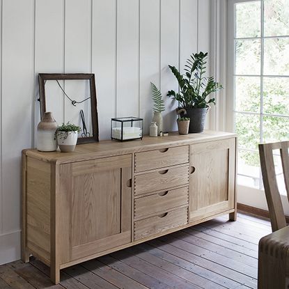 room with white striped wall wooden flooring and wooden drawers