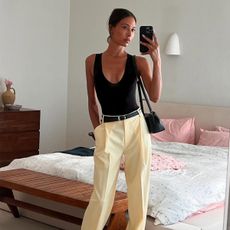 Tylynn Nguyen in a black tank top, yellow trousers, and a black shoulder bag.