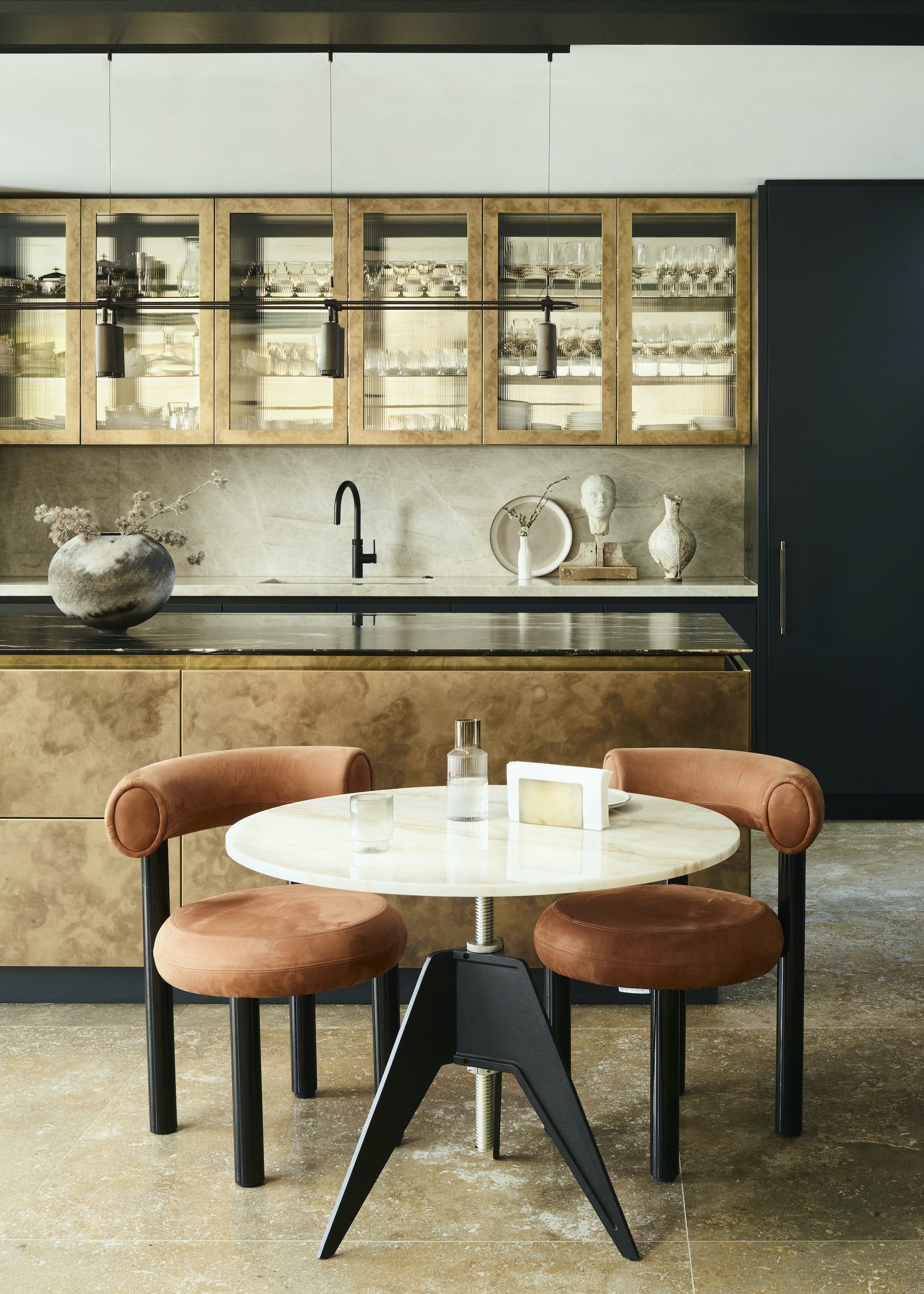 Kitchen with burnished brass island and round table with terracotta chairs