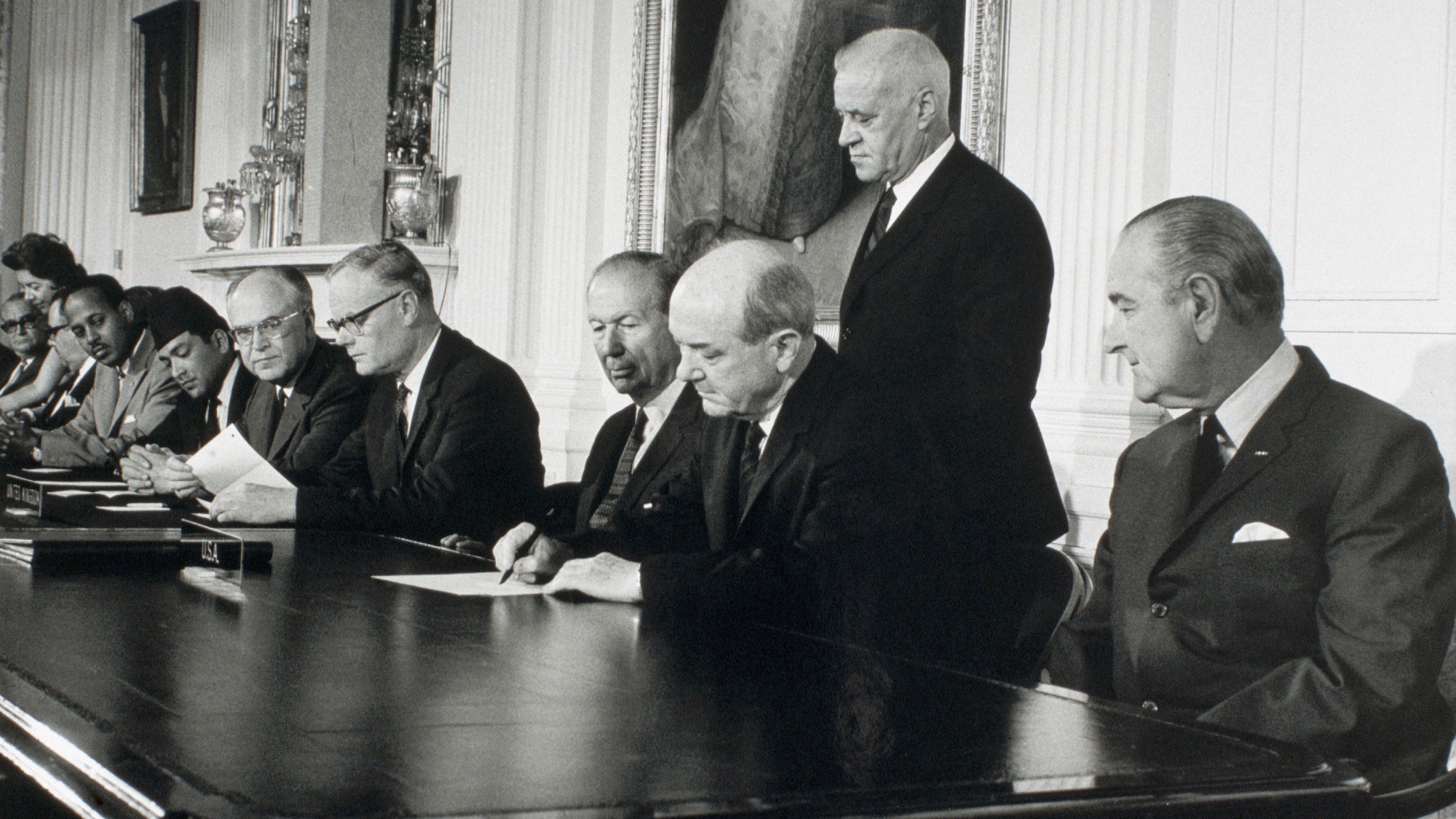 President Johnson looks on as Secretary of State Dean Rusk signs the treaty for the Non-Proliferation of Nuclear Weapons