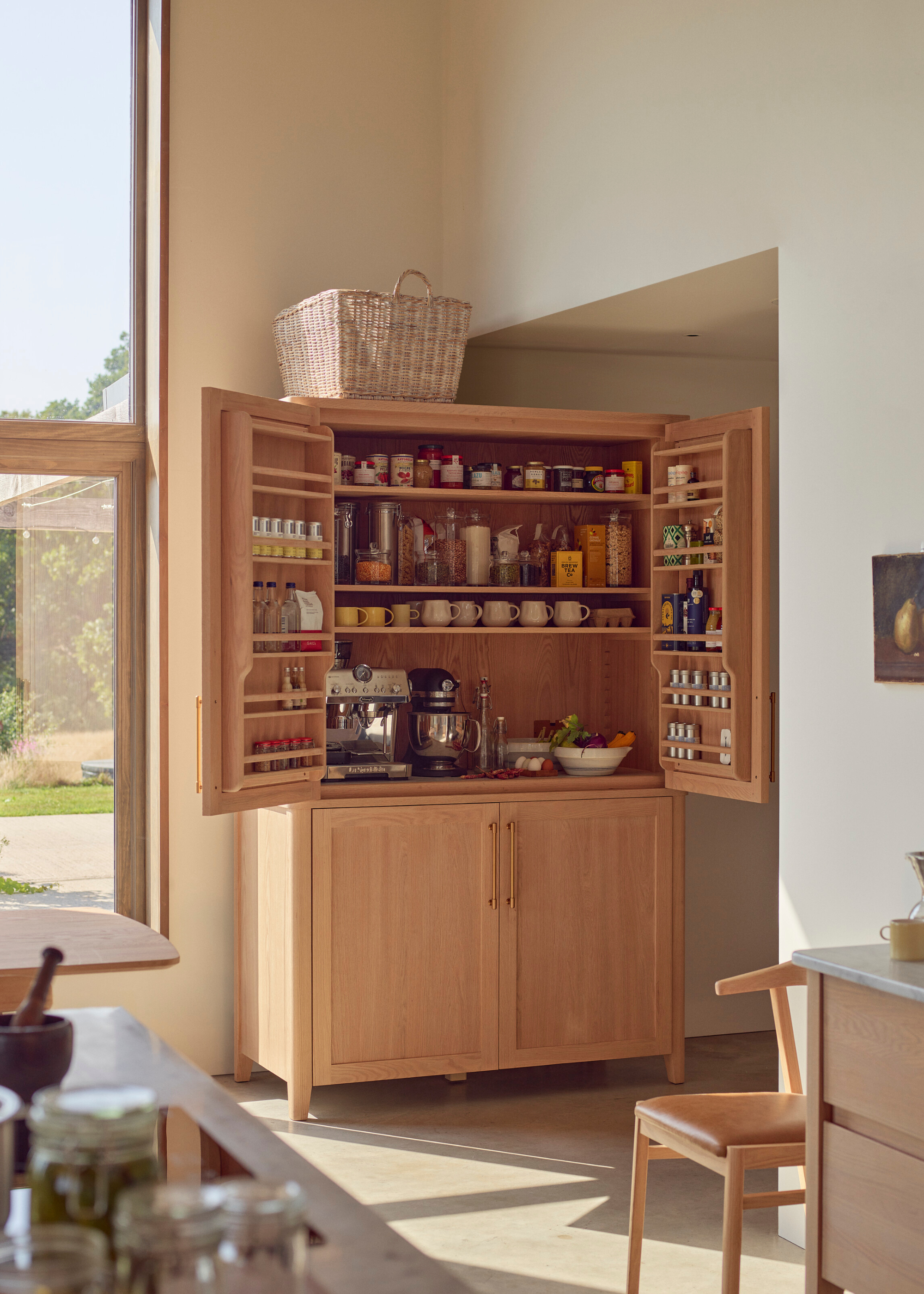 large freestanding wooden pantry, pictured open, with a coffee machine setup and lots of jars