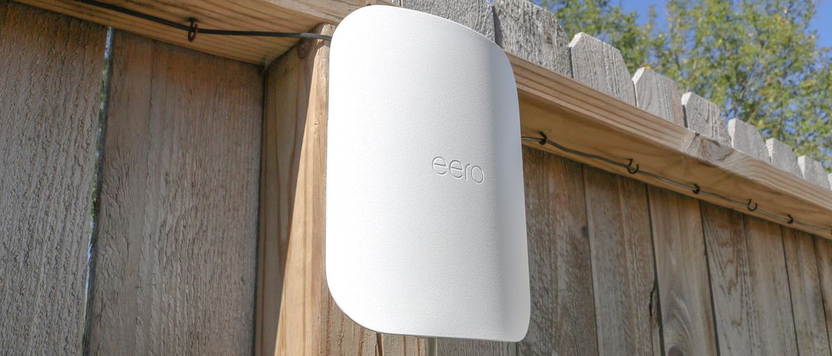 An Eero Outdoor 7 mesh extender mounted on a fence