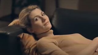 Jodie Whittaker lying on a couch in a tan sweater in Black Mirror