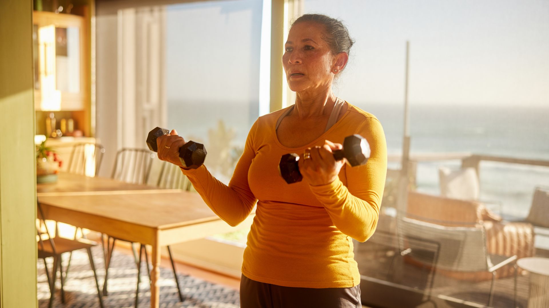 Woman lifting dumbbells at home in living room