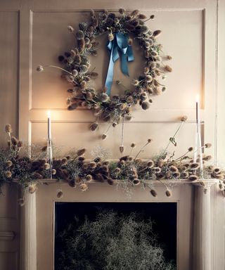 Fall mantel with dried thistles covering the mantel and forming a wreath with a blue ribbon