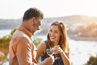 Happy woman toasting wineglass with man at terrace