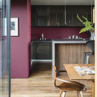 red wall kitchen with dark cabinets and dining table