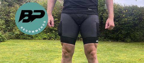 Man in cycling bib shorts with grass and hedge in background
